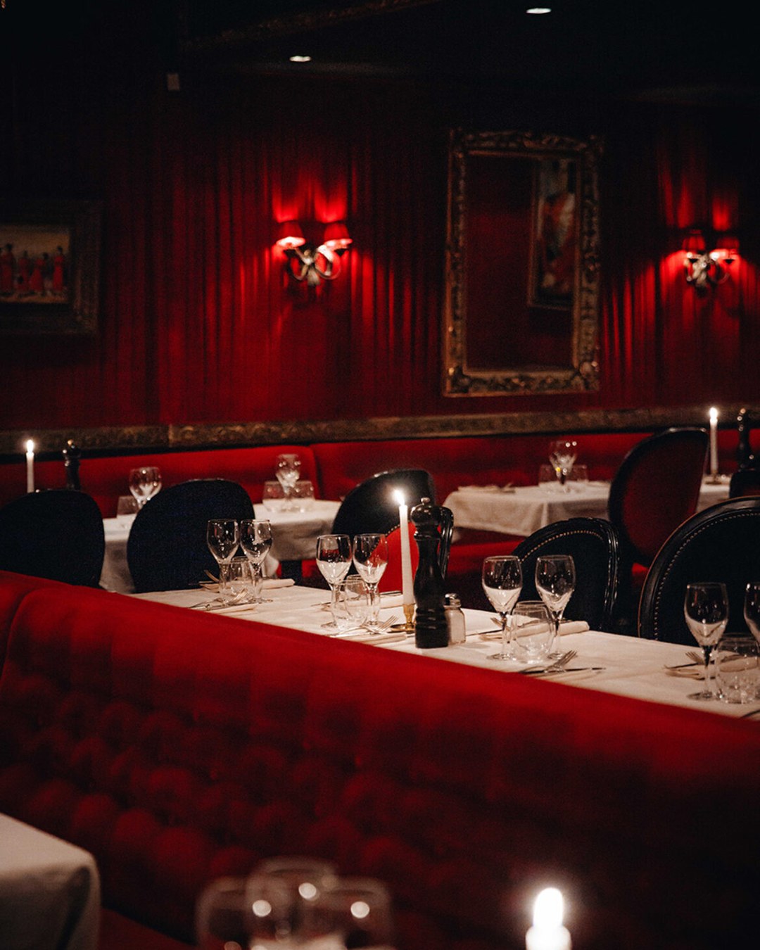 The crimson salon at Le Piaf Dubaï, chandeliers and gilt-framed portraits