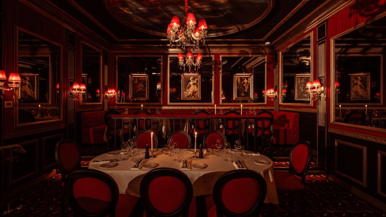 The crimson salon at Le Piaf Dubaï, chandeliers and gilt-framed portraits